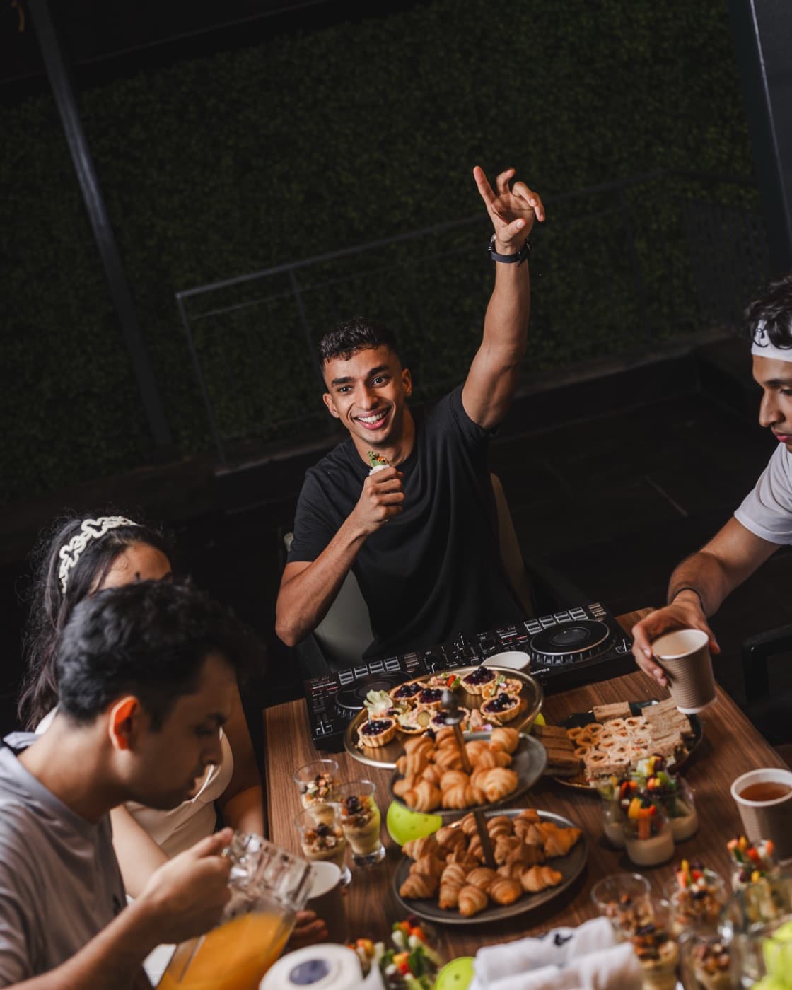 Friends laughing around a DJ deck and a table of food